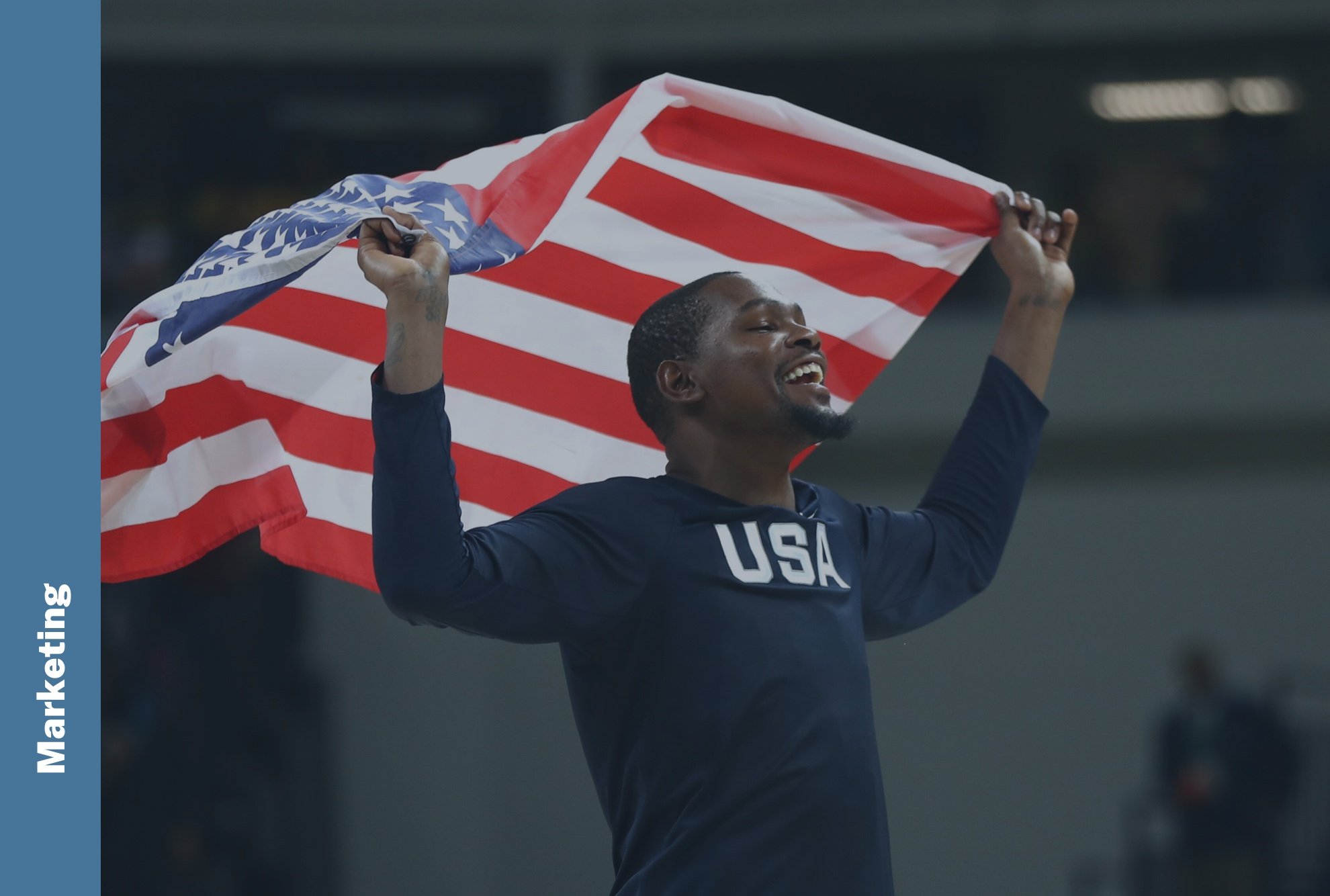 Marketing: A USA Basketball team member hoists an American flag over his head in celebration.
