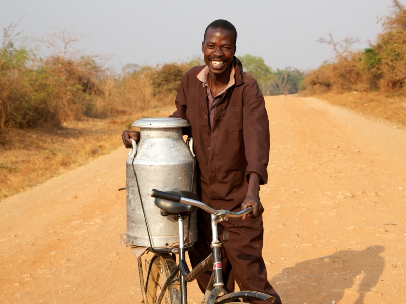 A smiling man in Africa using a bicycle for work